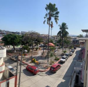 a street with cars parked in a parking lot with palm trees at Garzota Suites Gardens in Guayaquil