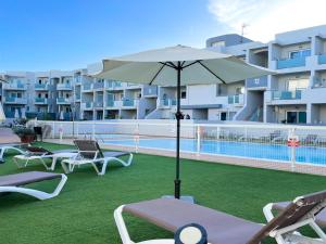 patio z krzesłami i parasolem przy basenie w obiekcie Payen Corralejo by Best Holidays Fuerteventura w Corralejo