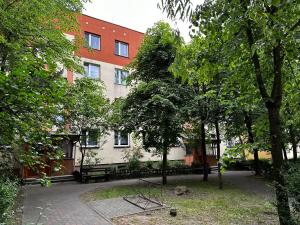 um edifício com um banco e árvores em frente em Nowy Apartament Lipowa em Hajnówka