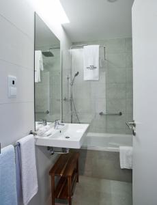 uma casa de banho branca com um lavatório e um chuveiro em Rochavau Hotel em Portimão