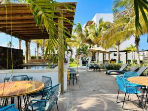 eine Terrasse mit Tischen, Stühlen und Palmen in der Unterkunft Palmilla 301,depa 5 min de playa in Mazatlán