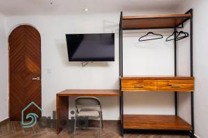 a room with a desk and a tv on a wall at VIca Guest House con piscina en la entrada de la Zona Hotelera in Cancún
