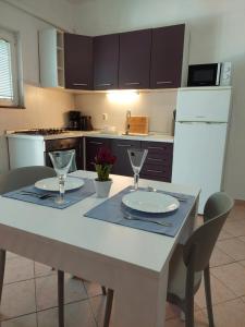 een keuken met een witte tafel met twee glazen erop bij Apartman Lucija in Seline