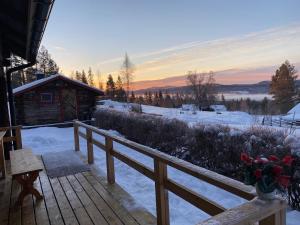 eine schneebedeckte Terrasse mit einer Hütte im Hintergrund in der Unterkunft Beautiful 4-5 persons Cottage in Alvdalen in Älvdalen