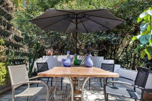 een houten tafel met stoelen en een parasol bij Stella Bed & Breakfast in Mexico-Stad