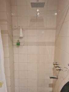 Una ducha de azulejos blancos con una botella verde en un estante. en Monoambiente a 300 metros del Obelisco, en Buenos Aires 16 fotos más