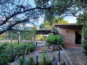 a stone house with a staircase in a garden at Villa La Lecceta surrounded by greenery and sea view with sunset in Costa Paradiso