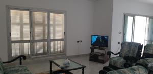sala de estar con 2 sillas y TV en Zomoroda North Coast Chalet by Solid Pro, en Dawwār Shindī Fannūsh
