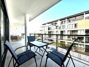 a balcony with a table and chairs and a building at New Condo with Pool, Gym, A/C, WiFi, King Size bed in Cancún