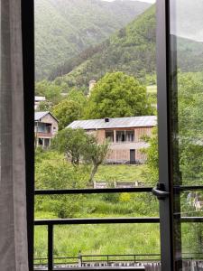 a view of a house from a window at Hotel Ailama Mestia in Mestia