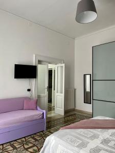 una camera con un divano viola e un letto di Alsimica Apartment a Taranto