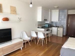 a kitchen with a table and white chairs in a room at Apartamento El Cine in Infiesto