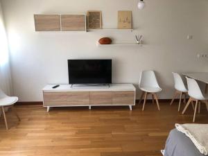 a living room with a tv on a cabinet and chairs at Apartamento El Cine in Infiesto