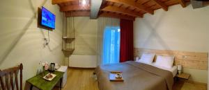 a bedroom with a bed and a television in it at Hotel Ailama Mestia in Mestia