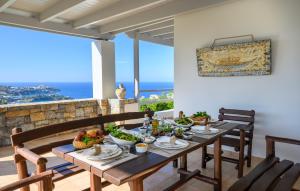 ein Esszimmer mit einem Tisch, Stühlen und Meerblick in der Unterkunft Wild Pear Villa in Agia Pelagia
