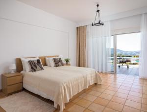 een witte slaapkamer met een bed en een groot raam bij Wild Pear Villa in Agia Pelagia