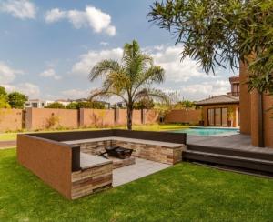 a backyard with a fire pit and a swimming pool at Pearl House in Centurion