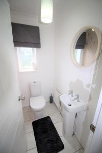 a bathroom with a toilet and a sink and a mirror at 3 Bed Detached - Sleeps 5 - Private Garden & Parking Plus Garage - Quiet Cul De Sac Location - Dog Friendly - Fast Wifi - Close to Motorway Access in Doncaster