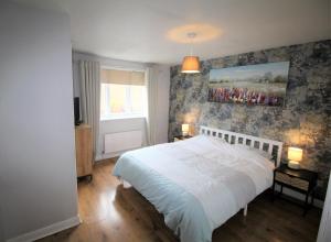 a bedroom with a bed and a painting on the wall at 3 Bed Detached - Sleeps 5 - Private Garden & Parking Plus Garage - Quiet Cul De Sac Location - Dog Friendly - Fast Wifi - Close to Motorway Access in Doncaster