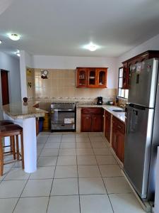 a kitchen with wooden cabinets and a stainless steel refrigerator at Acogedora Casa in Managua