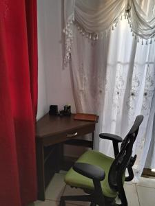 a desk and a green chair next to a window at Acogedora Casa in Managua