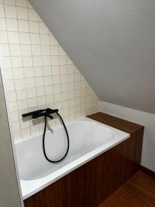 a bath tub with a black hose in a bathroom at Lille Bornholm in Banie Mazurskie