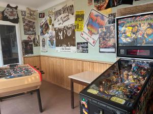 a room with a pinball machine and a table and posters at louisiana in Tercis-les-Bains