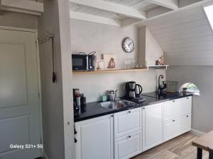 a kitchen with white cabinets and a sink and a clock at 't Achterhuis in Alteveer
