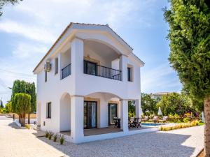 a white house with a balcony and trees at Sunny Paradise Luxury Villa With Pool & Hot Tub in Paphos City