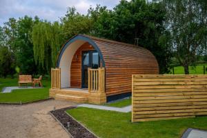 a small cabin in a park with a wooden fence at Willow Farm Glamping in Chester