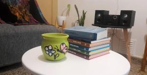 una pila de libros sobre una mesa con un jarrón encima en Pellegrini Departamentos muy confortable y bien ubicado en Godoy Cruz