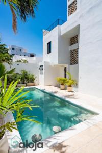 a swimming pool in front of a white house at VIca Guest House con piscina en la entrada de la Zona Hotelera in Cancún
