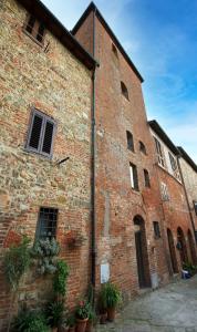 un viejo edificio de ladrillo con plantas delante de él en LA TORRE DEL CASTELLO, en Gambassi Terme