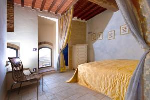 1 dormitorio con 1 cama y 1 silla en una habitación en LA TORRE DEL CASTELLO, en Gambassi Terme