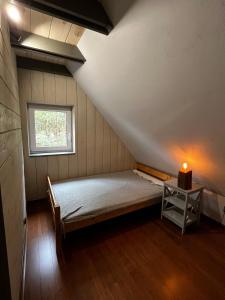 um pequeno quarto com uma cama e uma janela em Lille Bornholm em Banie Mazurskie