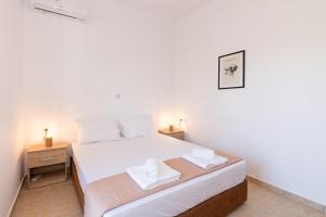 a bedroom with a white bed with two towels on it at Mysa Nature Apartments in Tragaki