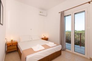 sypialnia z łóżkiem i dużym oknem w obiekcie Mysa Nature Apartments w mieście Tragaki