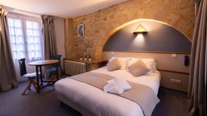 a hotel room with a large bed and a table at Hôtel des Récollets in Sarlat-la-Canéda