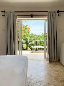 a bedroom with a bed and a sliding glass door at Surfbreak B&B in Cabarete