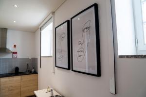 a bathroom with three framed pictures on the wall at HAGAH Alojamentos in Guimarães