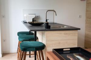 uma cozinha com um lavatório e bancos de bar verdes em HAGAH Alojamentos em Guimarães