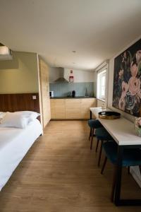 a bedroom with a bed and a table and a kitchen at HAGAH Alojamentos in Guimarães