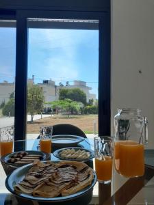 una mesa con platos de comida y vasos de zumo de naranja en Central House 1, en Palaia Epidavros