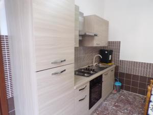 uma cozinha com armários brancos e um fogão em LA CASA DEL LIMONE - Via Umberto 477 em Roccalumera