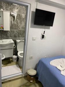 a bathroom with a toilet and a tv on the wall at Amida Family pansiyon in Istanbul
