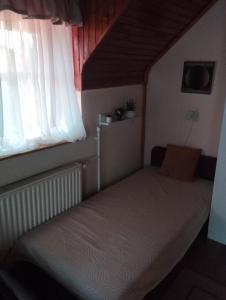 a small bed in a room with a window at Nóra Vendégház in Abádszalók