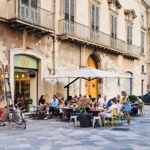 een groep mensen die aan tafels buiten een gebouw zitten bij Malìa bed and breakfast in Lecce