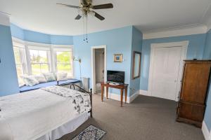 Schlafzimmer mit blauen Wänden, einem Bett und einem Deckenventilator in der Unterkunft The Georgetown Inn in Georgetown