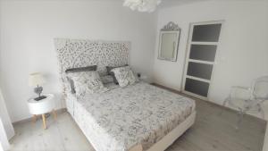 a white bedroom with a large bed and a window at LA MAISON DE MARIE A 8 mn des plages in Perpignan