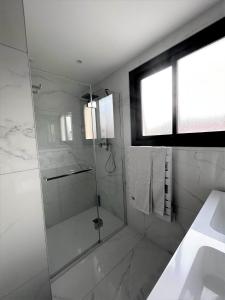 baño blanco con ducha y lavamanos en LA MAISON DE MARIE A 8 mn des plages, en Perpiñán